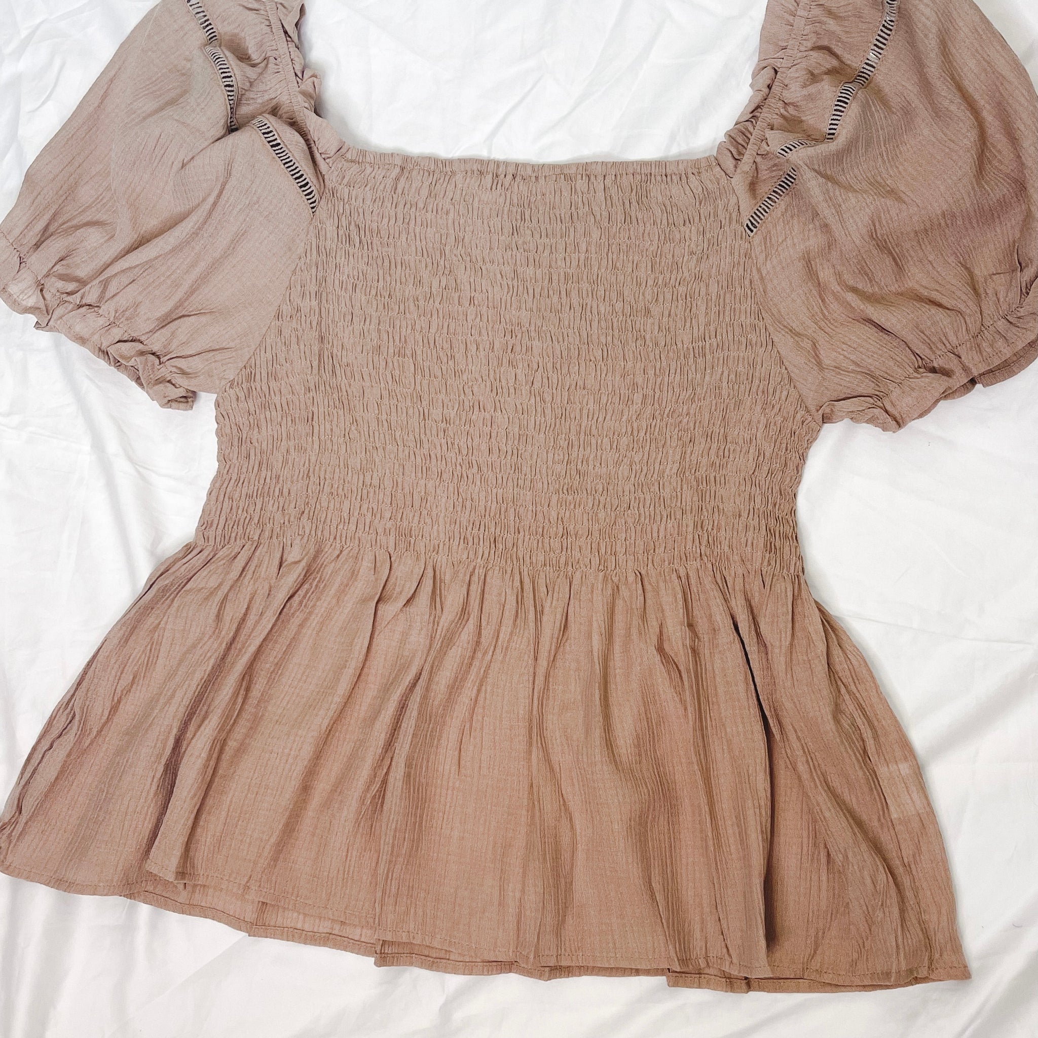 Mocha puff sleeve top with a square neckline, a shirred bodice, and a puplum style. This has a very nice stretch to it & is sheer material where it flares out under the bust. 